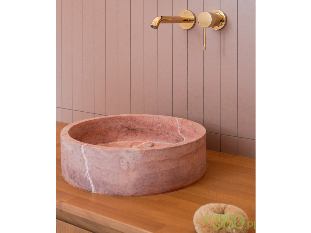 Złota bateria umywalkowa Grohe Essence z różową marmurową umywalką nablatową na drewnianym blacie