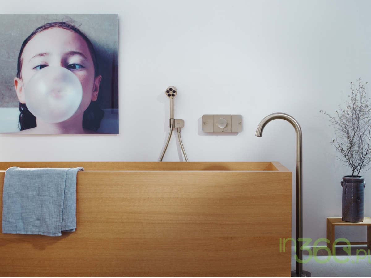Przestronna łazienka marki Axor, wyposażona w wolnostojącą wannę i elegancką baterię, jasne wykończenia oraz minimalistyczny design, idealna do luksusowych wnętrz.
