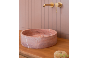 Złota bateria umywalkowa Grohe Essence z różową marmurową umywalką nablatową na drewnianym blacie