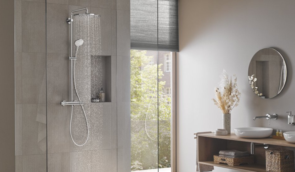 Nowoczesna łazienka z systemem prysznicowym Grohe Euphoria, deszczownicą i baterią termostatyczną na tle szarej ściany z wnęką, obok drewnianej szafki z dwiema umywalkami i okrągłymi lustrami