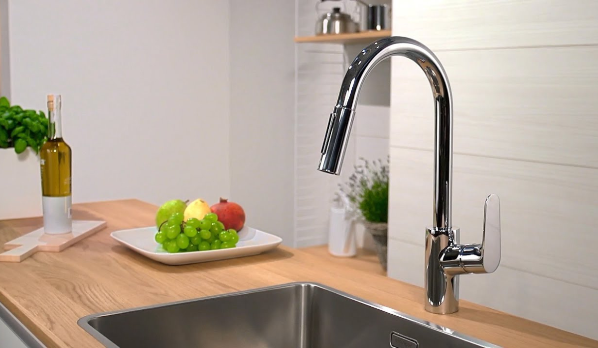 Bateria Hansgrohe Focus M z wyciąganą wylewką w wykończeniu chrom, zamontowana przy stalowym zlewie w nowoczesnej kuchni z drewnianym blatem