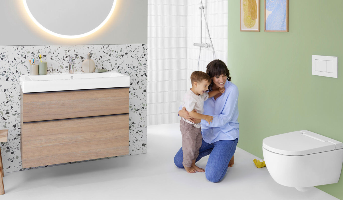 Mama klęcząca przy dziecku obok wiszącej miski WC