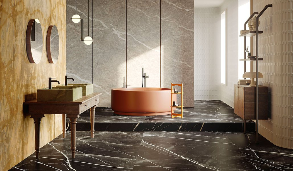 Eklektyczna łazienka w stylu Art Deco z charakterystyczną pomarańczową wanną, marmurowymi płytkami i designerskim oświetleniem.